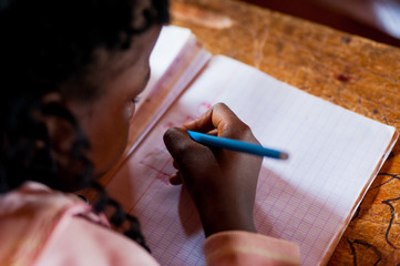 close up of young african girl during art lesson in school in africa on wooden desk