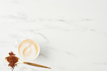 Concept of coffee background. Flat lay of coffee and golden spoon with ground coffee on marble background. Top view with copy space.