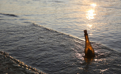 Bottle with message at the sunset