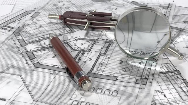 Blueprints - architectural drawings, compasses, a mechanical pencil, a magnifying glass on the surface of the architectural plan of a modern house	