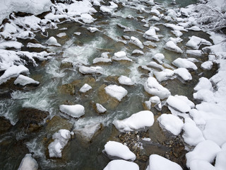 Snow covered rocks thrown into the riverbed