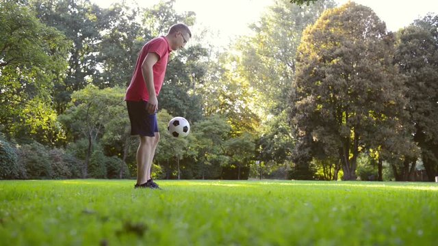 Closeup of feet juggling ball on grass in sunny park