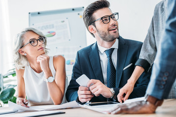 young caucasian businesspeople looking at colleagues in office