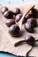 Whole inshell nutmeg scattered nuts on the burlap on blue wooden table.
