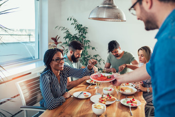 Group Of Happy Young Friends Enjoying Dinner At Home. Group of multiethnic friends enjoying dinner party