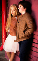 boy and girl teenagers posing against a brick wall background