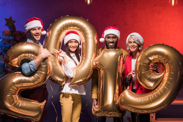 Fototapeta premium multicultural businessmen and businesswomen holding 2019 balloons at new year corporate party