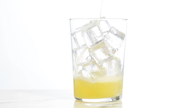 Vertiendo refresco de naranja en un vaso con hielos