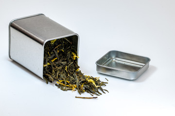 Dried green leaf tea in a small metal urn