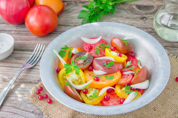 Tasty summer salad of sliced fresh colorful tomatoes, chopped red onion with white currant berries, olive oil,  and parsley. Healthy meal