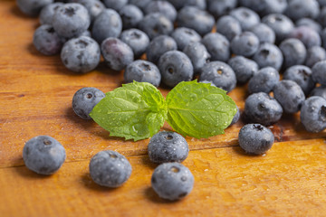Juicy and fresh blueberries with green mint leaves on a wooden table. Blueberries on wooden background.