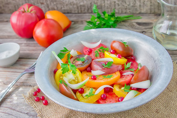 Tasty summer salad of sliced fresh colorful tomatoes, chopped red onion with white currant berries, olive oil,  and parsley. Healthy meal