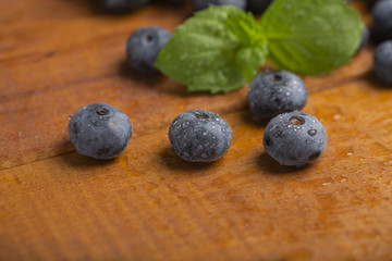 Fototapeta na wymiar Juicy and fresh blueberries with green mint leaves on a wooden table. Blueberries on wooden background.