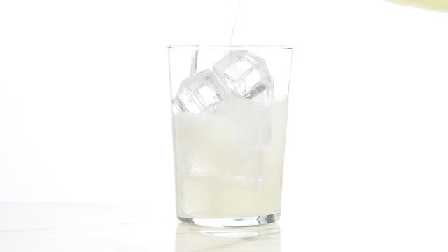 Vertiendo refresco de limón en un vaso con hielos