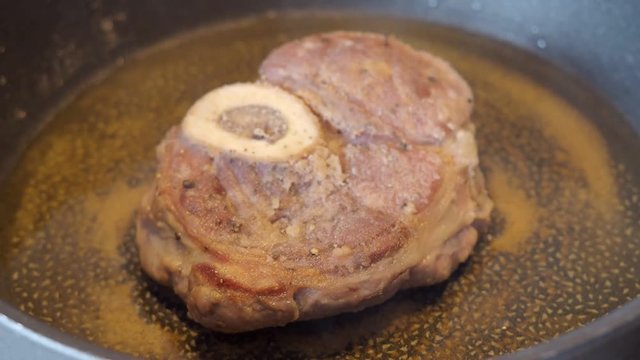 veal steak with marrowbone breaded in flour is fried in a pan