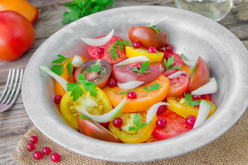 Tasty summer salad of sliced fresh colorful tomatoes, chopped red onion with white currant berries, olive oil,  and parsley. Healthy meal