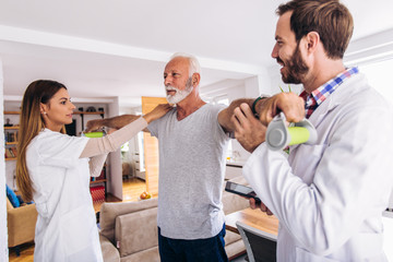 Obraz premium Man having chiropractic arm adjustment. Physiotherapy, sport injury rehabilitation. Senior man exercises in center for chiropractic.