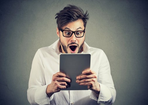 Man with tablet looking shocked