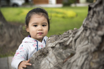 Little girl hugging a tree, looking up