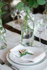 Wedding boutonniere on a napkin in a plate of wedding dinner. Decoration of a festive dinner with details.