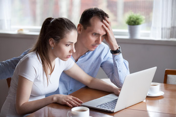 Upset millennial couple disappointed losing money in online lottery, worried man and woman look at laptop screen reading bad news, husband and wife get negative email from bank or eviction notice