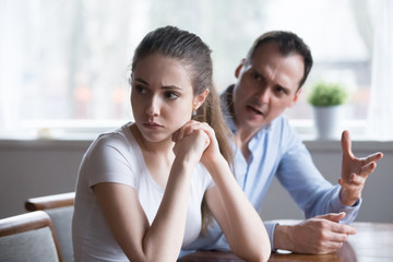 Offended woman sitting back to lover looking away avoiding talking, millennial couple having...