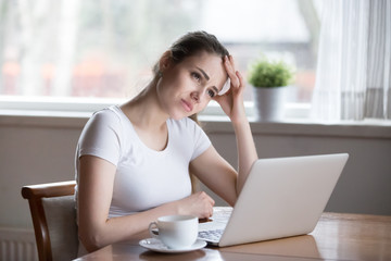 Unmotivated young woman frowning trying to remember important information, thoughtful girl sitting at laptop working looking for motivation, focused female thinking about problem solution