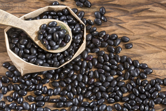 Raw black beans on the wooden background - Phaseolus vulgaris' Black turtle