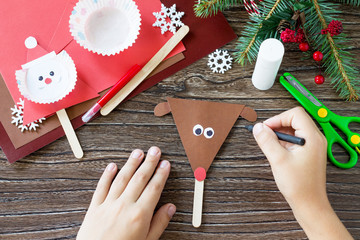 The child draws details Christmas Reindeer stics puppets. Handmade. Project of children's...