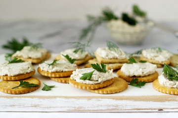 Snack from crackers and curd fish paste with herbs on a light background.