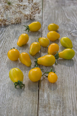 Fresh yellow small pear tomatoes on a sunny day in a wooden table. Delicious food. Vegetarian concept