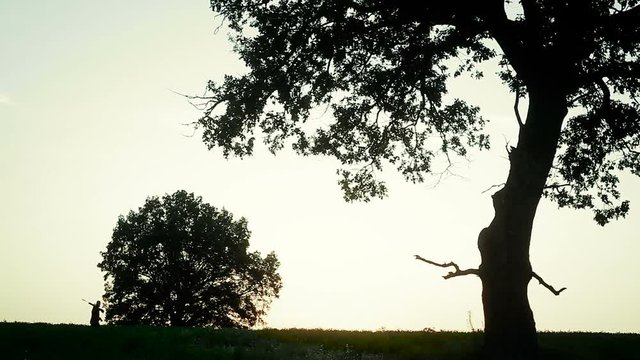 Hunter is at sunset on the field with a gun on his shoulder
