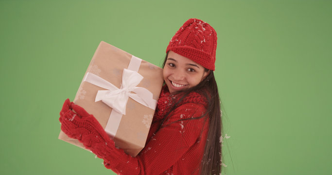 Latina girl playfully holding Christmas package around on green screen