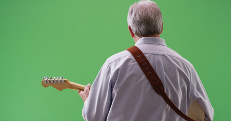 Rear view of mature white male playing electric guitar on greenscreen - Powered by Adobe