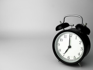 Alarm Clock isolated on white, in black with shadow, showing seven o'clock