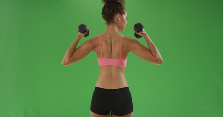 Black millennial girl lifts dumbbells working her biceps for green screen