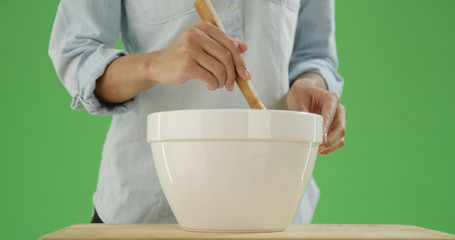 African american woman stirs a mixing bowl with a wooden spoon on green screen