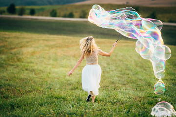 A young girl is running with huge soap bubbles