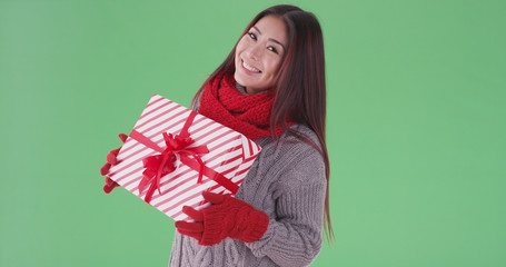 Happy asian woman holding presents in the snow on green screen