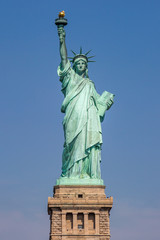 Fototapeta premium Widok na Statuę Wolności w Nowym Jorku, z czystym błękitnym niebem w tyle