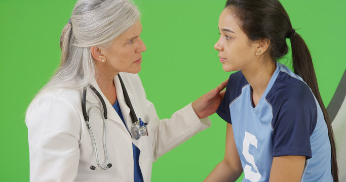 Young concussed soccer player is checked for dilated pupils on green screen