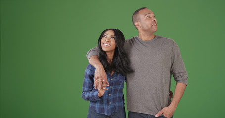 Happy young black couple looking around on green screen