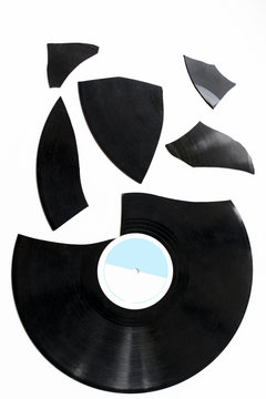 one big and many small pieces of broken vinyl on a white background. isolated