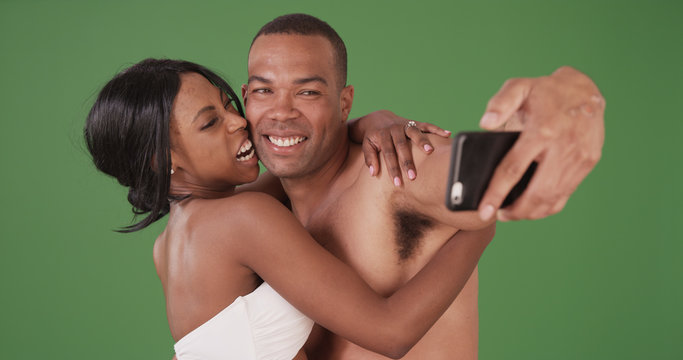 Loving couple in bathing suits taking selfies on green screen