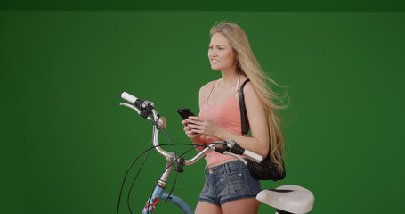 Female cyclist with phone waiting to meet up with friend to go on bike ride
