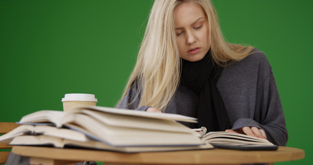 Pretty young woman reading textbook for class on green screen