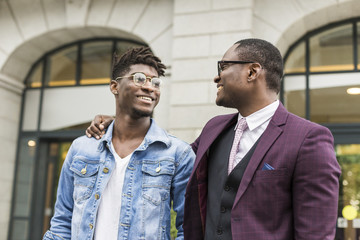 two young and stylish African American men in the city smiling and talking. father and adult son relationship