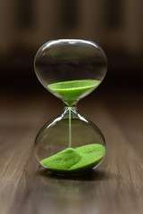 Hourglass with green sand on a blurred background