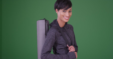 Obraz premium Healthy black woman with yoga mat waiting for class to start on green screen
