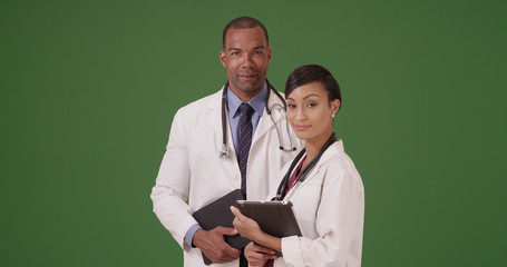 Two African American doctors holding their tablets on green screen